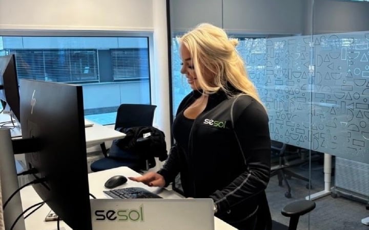 Selger i Sesol står ved pulten sin og jobber på pc