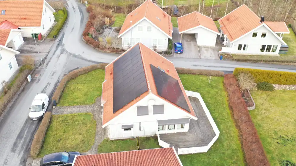 Solcellsanläggning på rött hustak i villaområde
